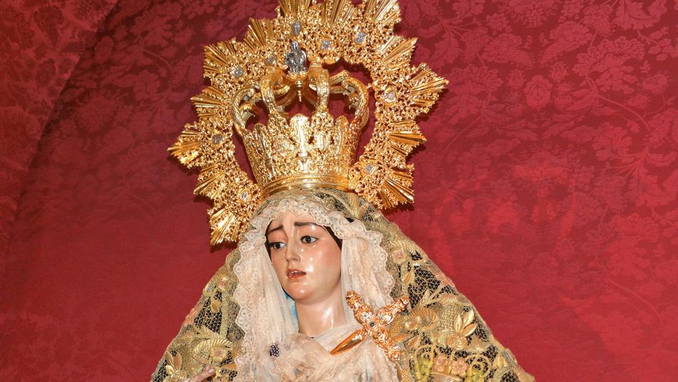 Statue of Virgin Mary with the colorful, shiny crown, near the red wall with patterns
