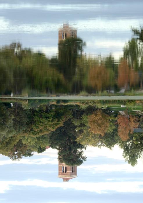 Beautiful and colorful trees and tower, with the reflections in the lake, in fall, upside down