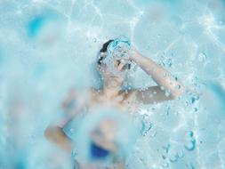 photo of a teenager under water with bubbles