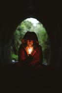 Man in hood, with the flame, in the building, at background with the green trees