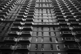 Black and white low angle shot of the building with windows and balconies