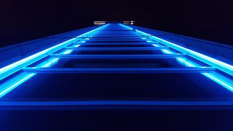 Bottom view of the building facade with bright, blue lights