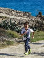 happy boy running along the coast