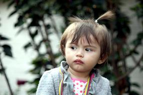 Portrait of the cute, Colombian child girl near the plants