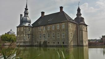 photo of a castle with a moat against a gray sky