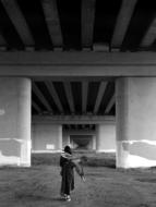 black and white photo of a man with a kite under a bridge