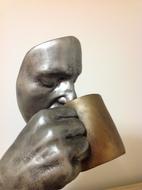 Iron face figurine with a cup
