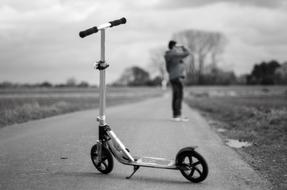 black and white photo of a parked scooter in a park