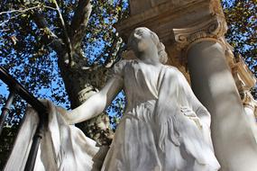 Beautiful, white, marble sculpture of the thinking woman, near the decorated columns in Madrid, Spain