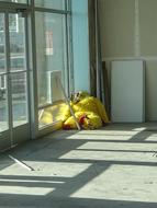 Yellow and red chicken costume in the corner, inside the building, in light and shadow