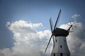Beautiful, white windmill, at blue sky with white clouds on background