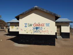 School building with the colorful "Change The World" graffiti in South Africa, at blue sky on background