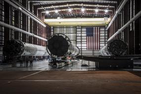 people at falcon rockets in hangar with American Flag on wall