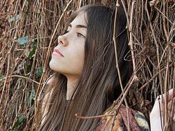 Portrait of the beautiful girl with long hair, among the colorful plants