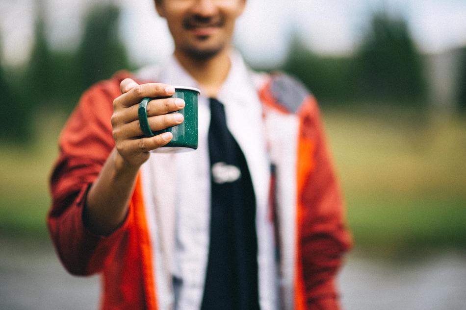 Smiling man, with the green cup in the hand, at blurred background