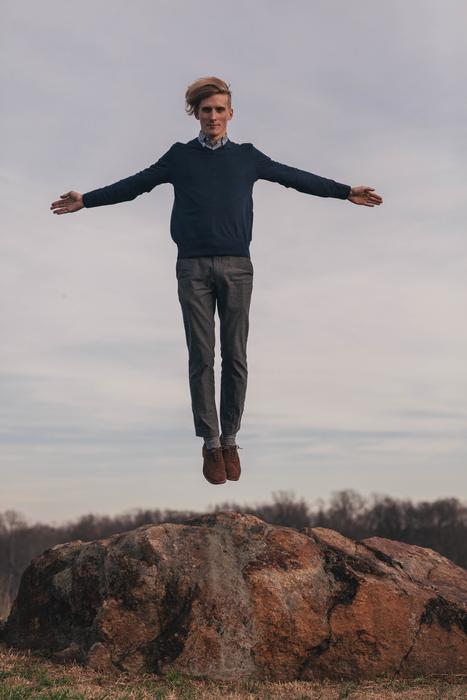 young caucasian Man in jump above rock on seaside