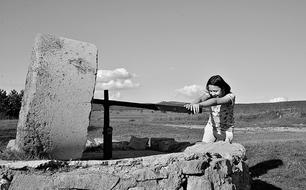 monochrome picture of Child girl plays with big stone in countryside