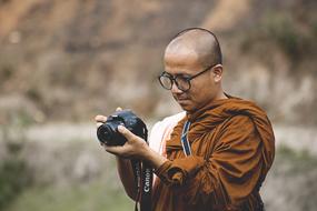 Portrait of the man, in glasses, with the camera, outdoors