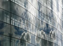 reflection of clouds in the windows of a glass building