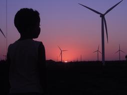 silhouette of a boy on the background of a field with wind turbines