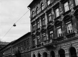 Black and white photo of the beautiful, old building with the cables, under the cloudy sky