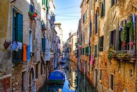 Beautiful canal with the boats, among the colorful buildings with the plants, in Venice, Italy