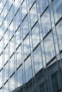 sky and clouds are reflected in the windows of a skyscraper
