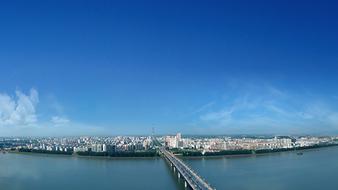 City panorama and panorama of the bridge above the water at blue sky with white clouds in Changsha, China