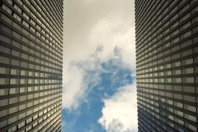 two skyscrapers and blue sky with clouds in between