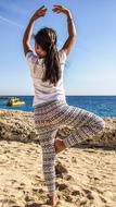 Back view of the girl, dancing on the beautiful, sandy beach