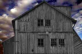 weathered grey wooden barn at cloudy sky