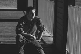 Man sits on walk path, black and white