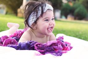 cheerful baby on the grass on a blurred background