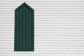 exterior of dark green door and white wooden wall