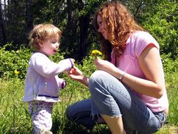 Baby Girl and mother with Dandelions on meadow