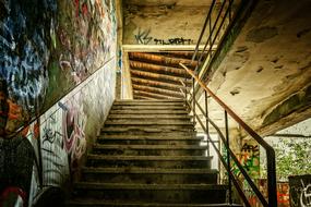 Old staircase, with the colorful graffities, in the abandoned building, in light and shadow