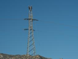 Electrical tower, with the workers, on the beautiful and colorful mountain, at blue sky on background