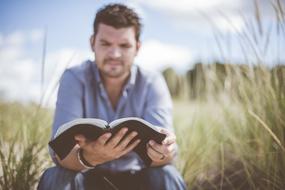 man reading a book on the field