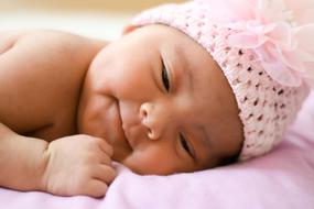 Portrait of a cute, newborn baby girl in pink hat