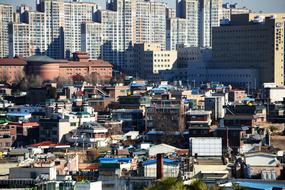 photo of single-story buildings in the background of urban multi-storey buildings