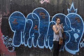 girl with a smartphone on the background of a wall with graffiti