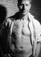 black and white photo of a tattooed man in a white shirt