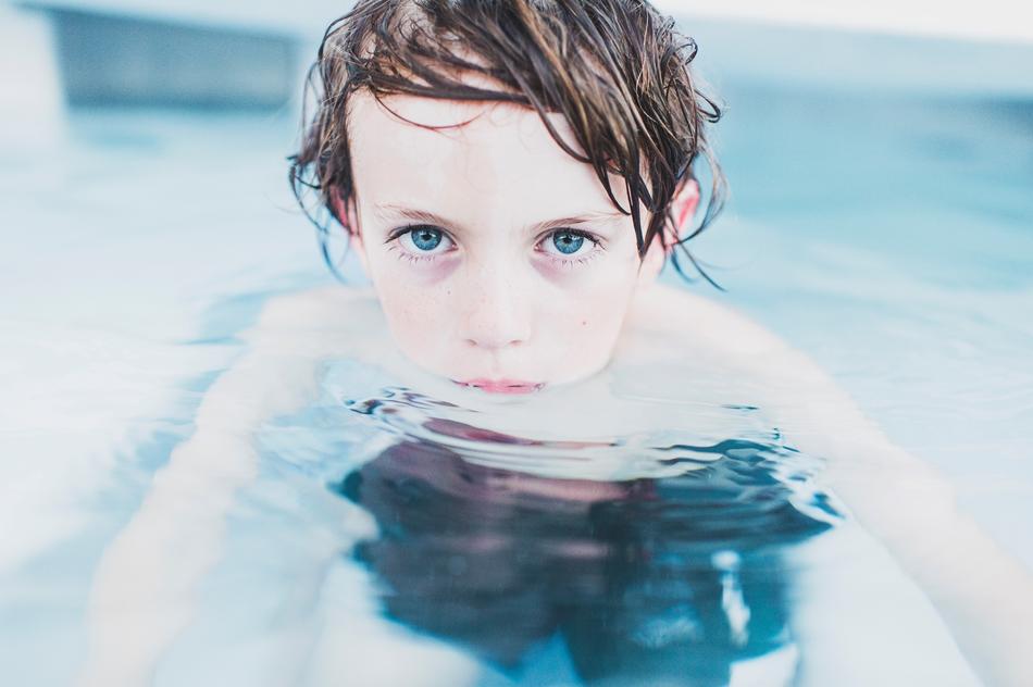 Portrait of a wet child with the blue eyes, swimming in the clear water