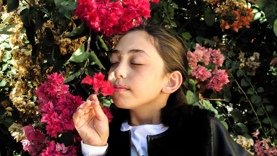 Happy child Girl smells flowers in Garden