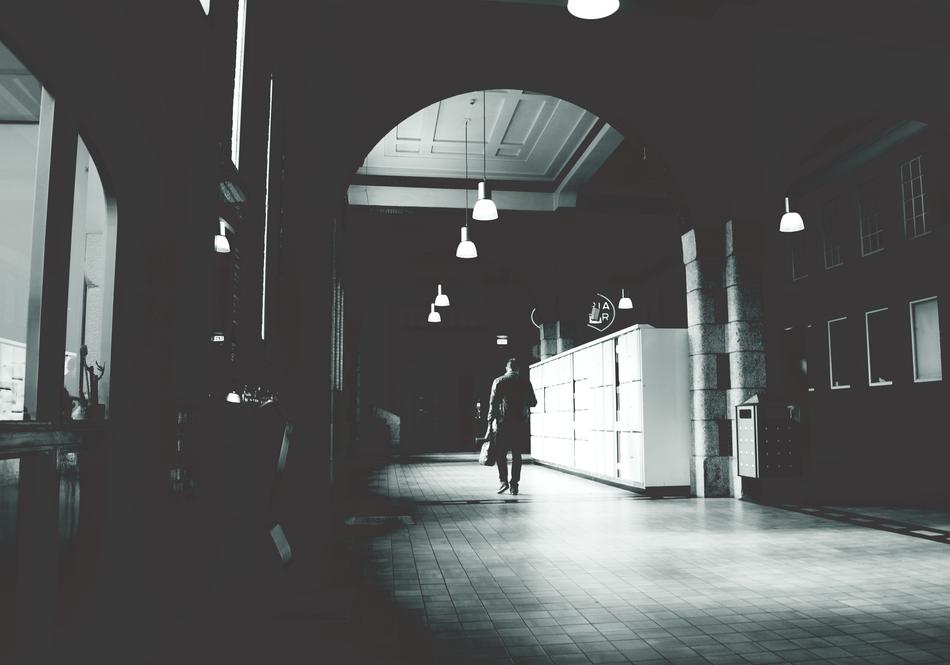 black and white photo of a man walking down the hallway