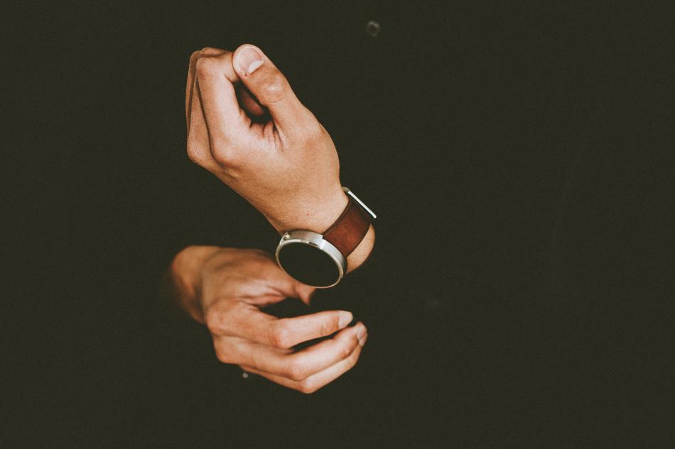 male hand with wristwatch at black background