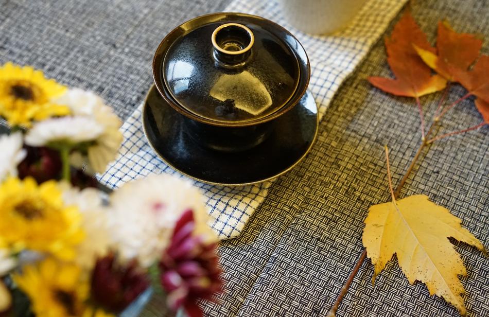 Tea Cup with cover, autumn flowers and leaves on table at Home