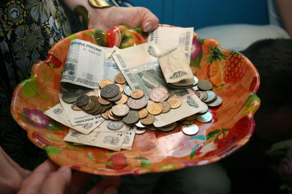 Colorful Ruble banknotes and coins on the colorful plate with fruits, in the hands