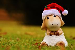 Beautiful and cute sheep figure with red and white Christmas hat on the grass