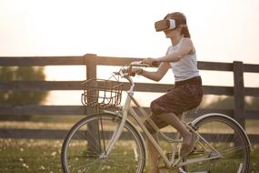 Augmented Reality, girl with vr headset riding Bicycle in countryside